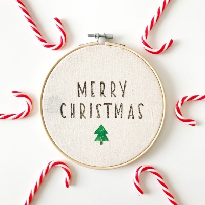 Aro de bordado com mensagem de Natal rodeado por bengalas de doces listradas