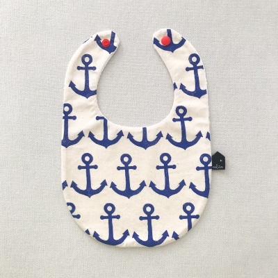 Babete de bebé branco com âncoras azuis e botão vermelho