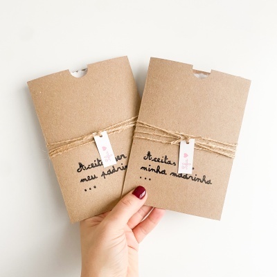 Duas embalagens castanhas com corda e etiquetas com texto manuscrito em português