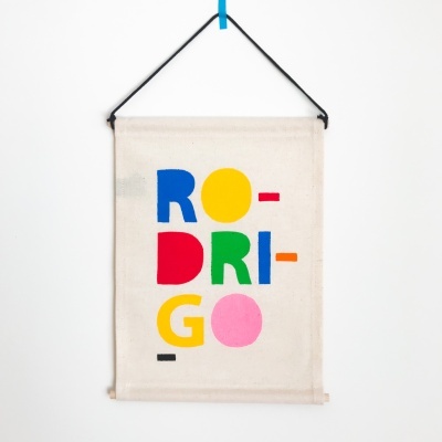 Mural creme pendurado com letras coloridas RO-DRI-GO