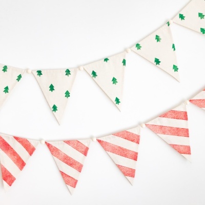 Bandeirolas de tecido brancas com árvores verdes e riscas vermelhas em fio branco