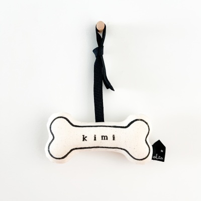 Brinquedo para cão em forma de osso branco com texto 'kimi' preto
