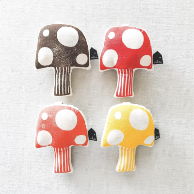 Brinquedos de tecido em forma de cogumelo coloridos com manchas brancas.