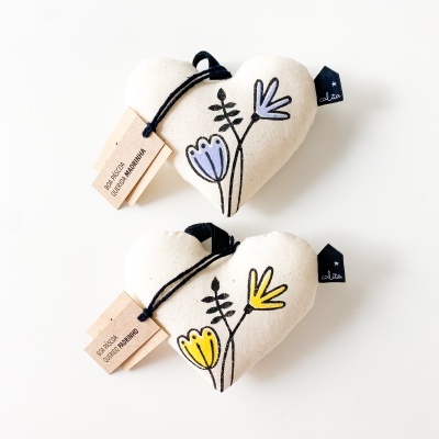 Dois corações de tecido creme bordados com flores coloridas e etiquetas com texto