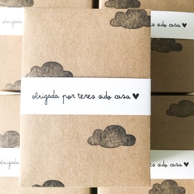Caixas de papelão com impressão de nuvens e faixa branca com texto em português.