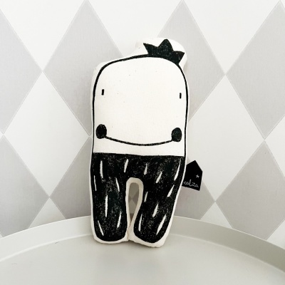 Almofada de boneco branco e preto com rosto sorridente e etiqueta calita