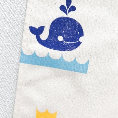 Tecido branco com estampa de baleia azul e ondas azuis claras