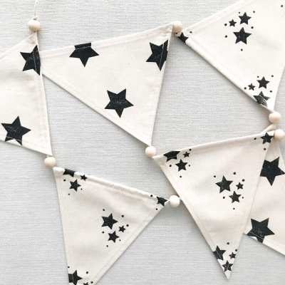 Bandeirola triangular branca com estrelas pretas e bolas de madeira clara
