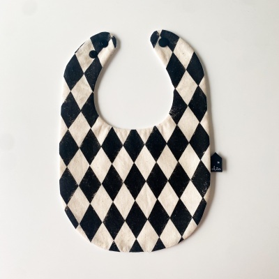 Babete para bebé branco e preto com padrão de losangos e fecho de pressão.