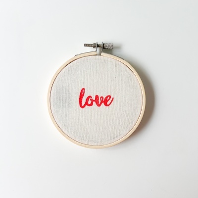 Aro de bordado com tecido branco e palavra love em vermelho