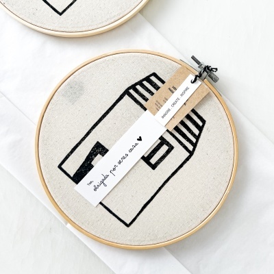 Bastidor de bordado com bordado preto de casa e etiquetas em fundo branco