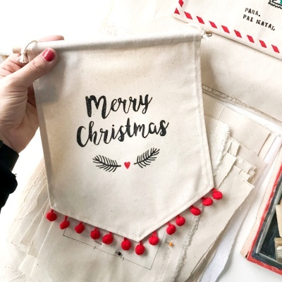 Saco de pano branco com mensagem de Natal em preto e elementos decorativos vermelhos