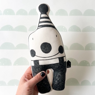 Brinquedo de tecido preto e branco com padrão de riscas e círculos, segurado por uma mão