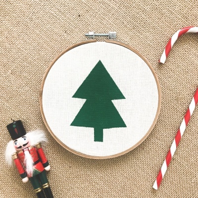Aro de bordado com árvore verde, soldadinho de madeira e bastões de doces