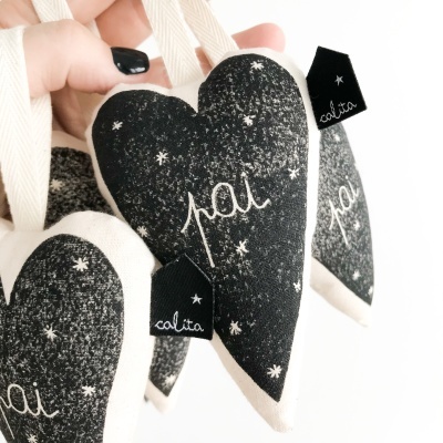 Suspensão em tecido em forma de coração preto com palavras 'pai' e etiquetas 'calita'