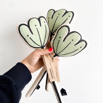 Flores artificiais verdes com caules e etiqueta em mão masculina