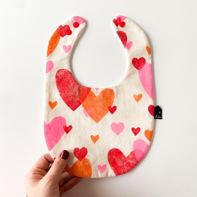 Babete de bebé com corações coloridos em fundo branco