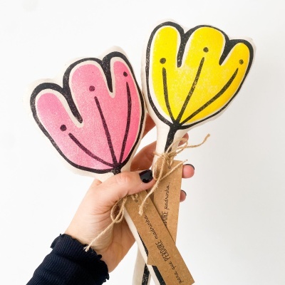 Abanadores de mão coloridos em forma de flores segurados por uma mão