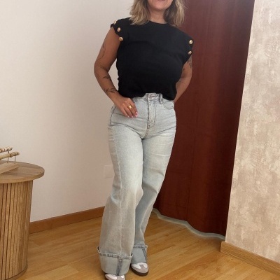 Mulher com camiseta preta e calças de ganga em ambiente interior