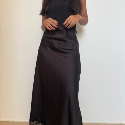 Mulher com vestido preto acetinado com renda na borda inferior