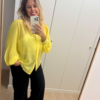 Blusa amarela transparente com mangas plissadas e calças pretas largas em selfie no espelho.