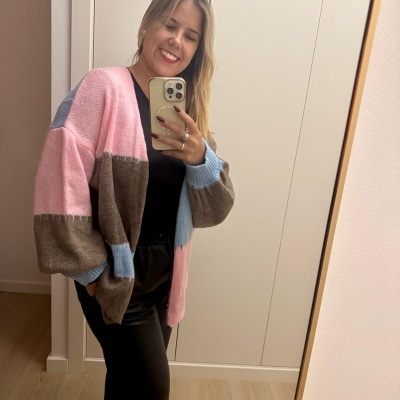 mulher vestindo cardigan colorido com cea e preto diante de espelho