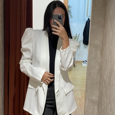 Casaco branco com ombros franzidos e bolso de aba, pessoa a tirar selfie em espelho