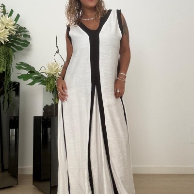 Vestido comprido branco com faixas pretas verticais usado por mulher em ambiente interior com plantas ao lado