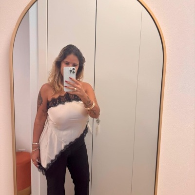 Mulher a tirar selfie num espelho com blusa branca com renda preta e calças pretas