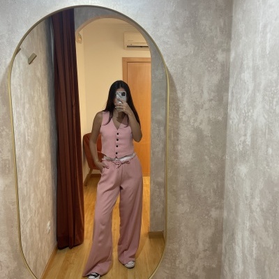 Espelho oval mostra mulher com conjunto rosa e sapatos pretos e brancos