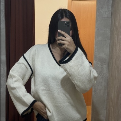 Camisola branca felpuda com detalhes pretos nas bordas vista num espelho.