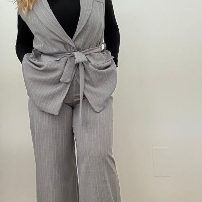 Conjunto feminino cinzento riscas com colete e calças, camisa preta de gola alta e sapatos cáqui