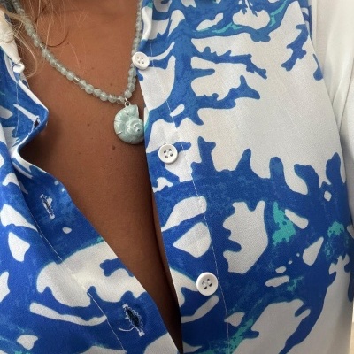camisa azul e branca com padrão de coral e colar com pingente de concha