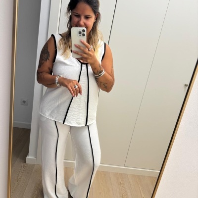 Mulher com conjunto branco de top e calças largas com linhas pretas verticais