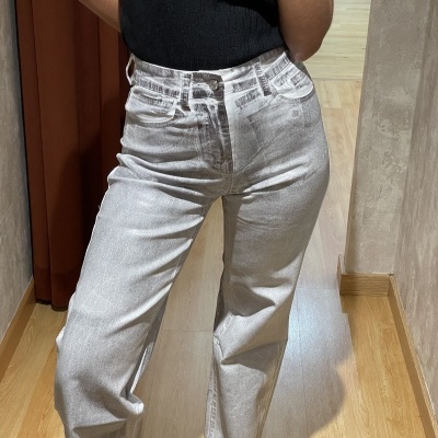 Calças de ganga bege claro de corte largo usadas por dentro de casa