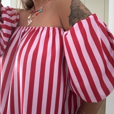 Blusa ombro a ombro riscas vermelhas e rosas com colares coloridos e tatuagem no braço