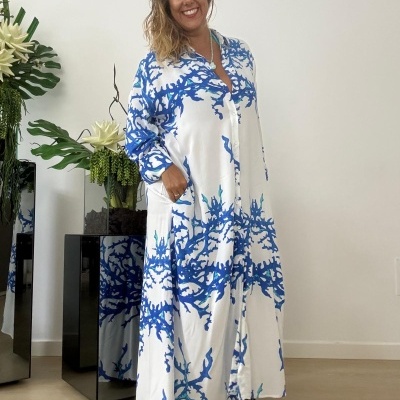 Vestido longo branco com padrão azul usado por mulher em ambiente interior