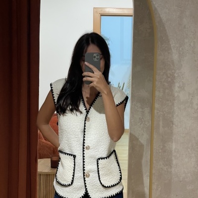 Colete branco com bordas pretas refletido em espelho arqueado interior.