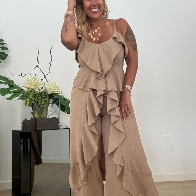 Mulher com macacão bege texturizado com folhos em ambiente interno