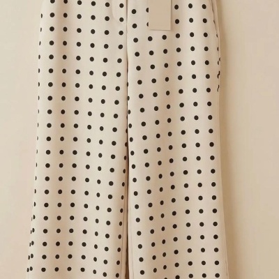 Calças brancas com bolinhas pretas penduradas num cabide