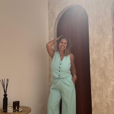 Macacão feminino verde-água com botões, parede clara e arco interior.