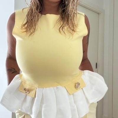 Top amarelo claro com folho branco e botões dourados, usado por mulher