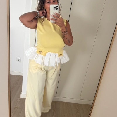 Mulher com top amarelo e calças largas amarelo claro a tirar selfie em espelho