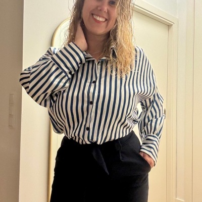 Pessoa com camisa riscada azul e branca e calças pretas em ambiente interior