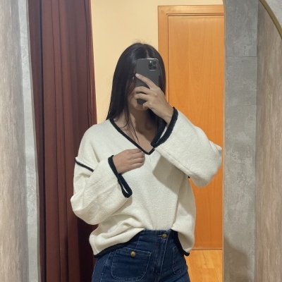 Camisola branca felpuda com detalhes pretos e jeans azul escuro numa divisão interior