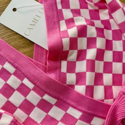 Vestido rosa e branco xadrez com etiqueta CAMÉLIA sobre madeira