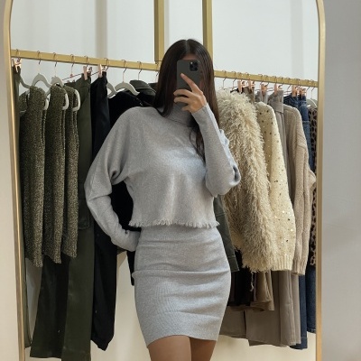 Conjunto feminino cinzento claro em malha com gola alta, camisola cropped e saia justa refletido em espelho
