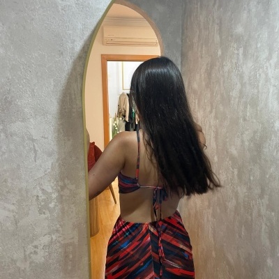 Vestido comprido com padrão abstrato vermelho, preto e azul, costas nuas, num corredor cinzento.