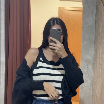 mulher com top às riscas e jeans num espelho com porta e ar condicionado no fundo