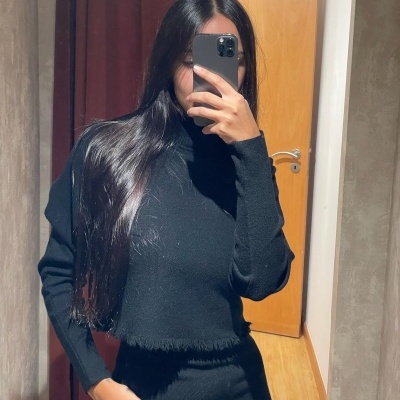 Mulher com vestido de malha preto de gola alta em selfie interior